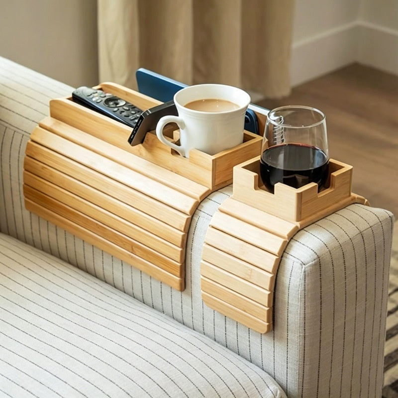 Bamboo couch-arm tray holding a coffee mug, phone, remote and wine glass on a striped sofa